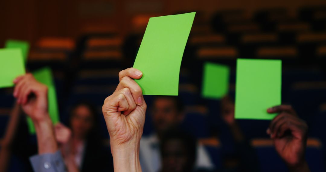 Hands Holding Green Cards for Voting in Decision-Making Process