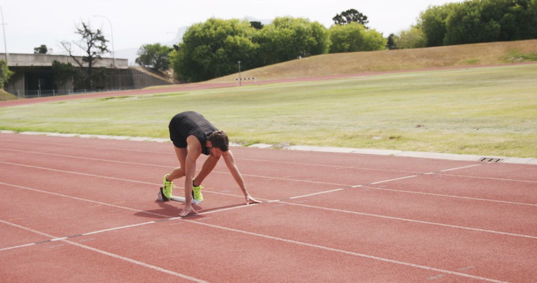 Male Athlete Preparing for Sprint on Outdoor Track - Free Images, Stock Photos and Pictures on Pikwizard.com