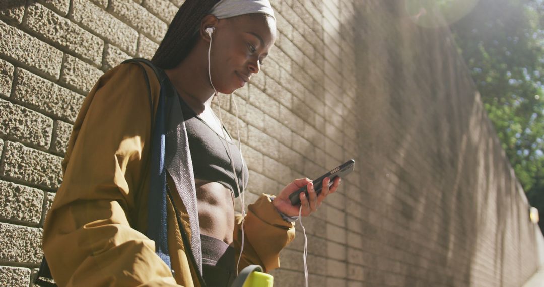 Active Young Woman Listening to Music While Walking Outdoors - Free Images, Stock Photos and Pictures on Pikwizard.com