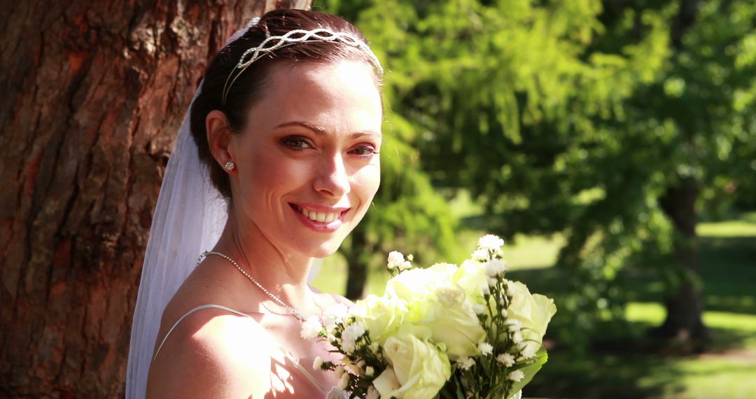 Smiling Bride Holding Bouquet Next to Tree in Nature - Free Images, Stock Photos and Pictures on Pikwizard.com