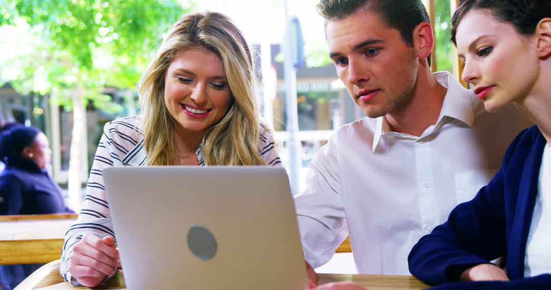 Friends Collaborating on Laptop in Cozy Cafe Setting