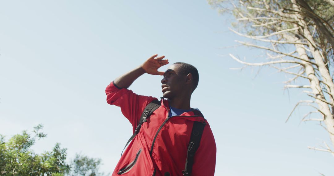 Young African American Man on Adventure Hike Shields Eyes from Sun - Free Images, Stock Photos and Pictures on Pikwizard.com