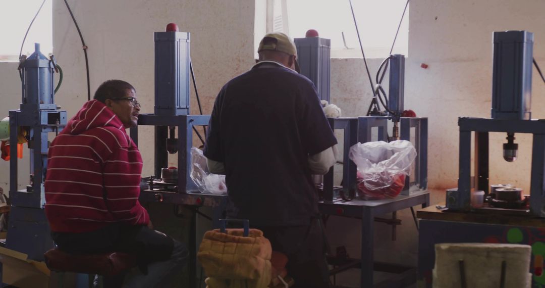 Technicians Operating Hydraulic Press Machines in Manufacturing Workshop