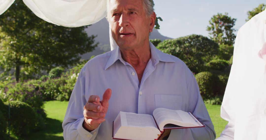 Elderly Man Giving Speech Holding Open Book Outdoors - Free Images, Stock Photos and Pictures on Pikwizard.com