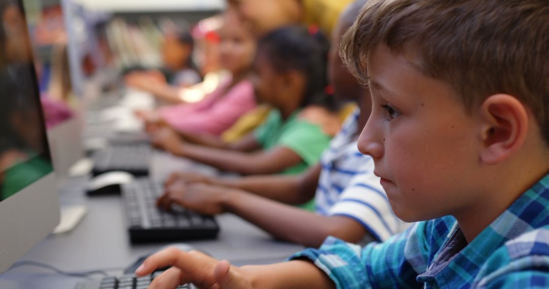 Focused Boy Using Computer in Classroom of Diverse Students