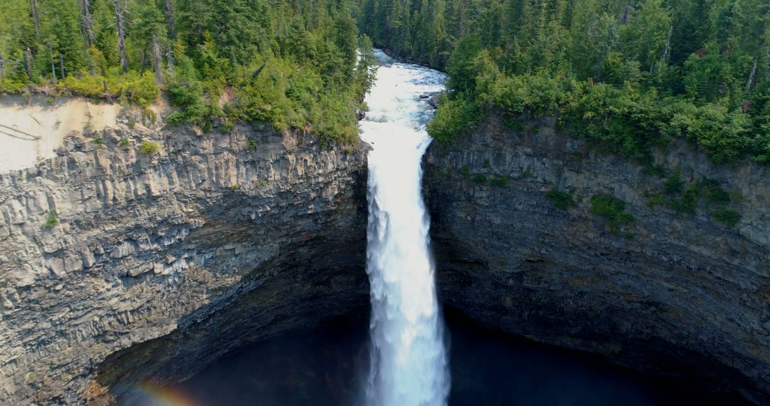 Aerial view of a majestic waterfall cascading down a rugged cliff surrounded by dense forest - Free Images, Stock Photos and Pictures on Pikwizard.com