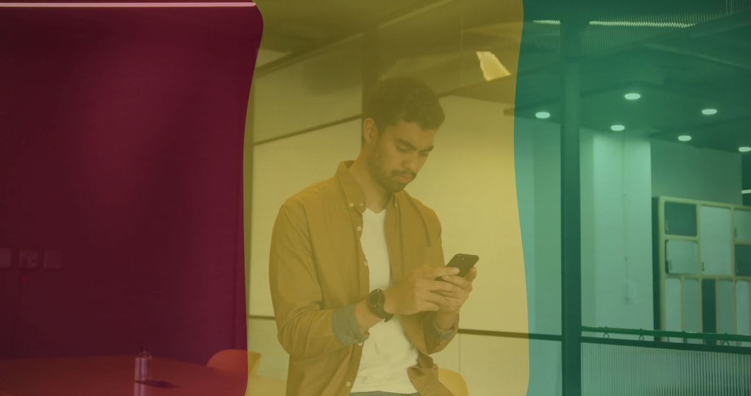 Man Checking Smartphone in Modern Office with Colorful Glass Panels