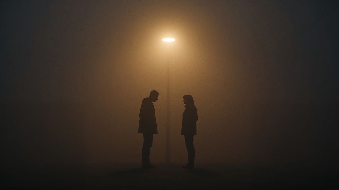 Silhouetted Couple Beneath Streetlamp in Foggy Night Ambiance