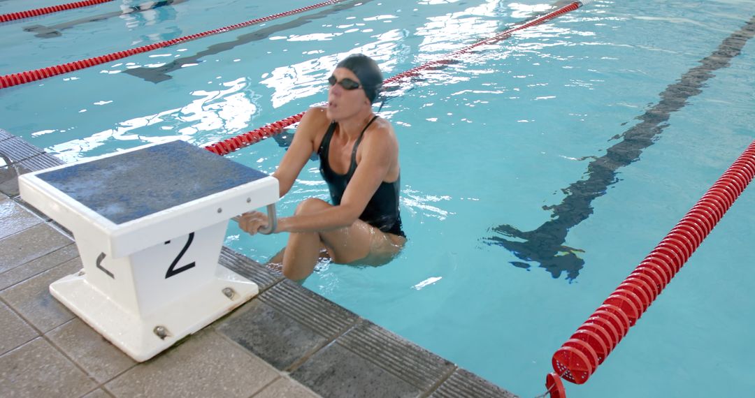 Female Swimmer Resting Poolside During Swim Training