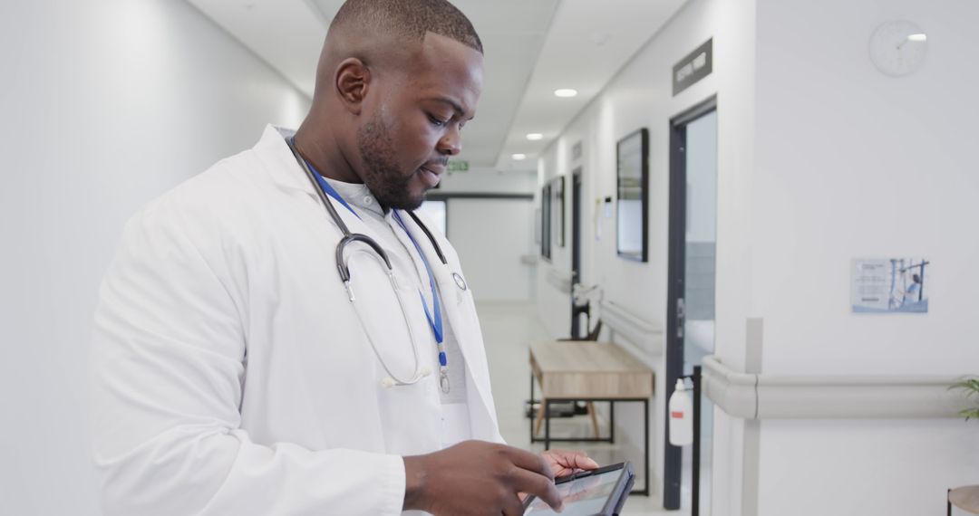 Male African American Doctor Using Tablet in Hospital Corridor - Free Images, Stock Photos and Pictures on Pikwizard.com