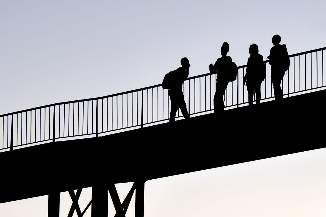 Silhouette of Four People Walking on Bridge at Sunset - Free Images, Stock Photos and Pictures on Pikwizard.com