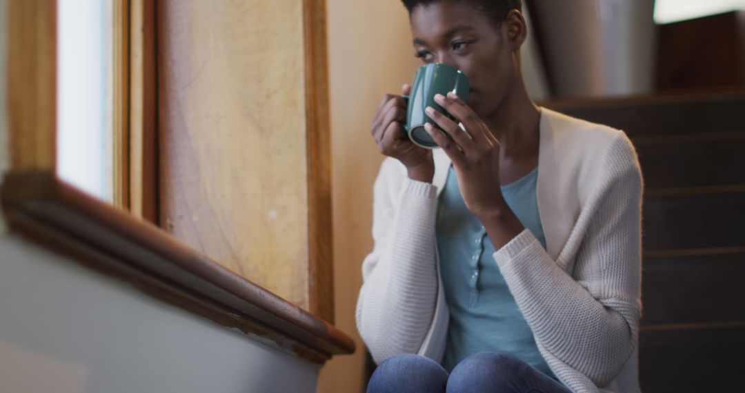 Contemplative Woman Sitting by Window with Coffee - Free Images, Stock Photos and Pictures on Pikwizard.com