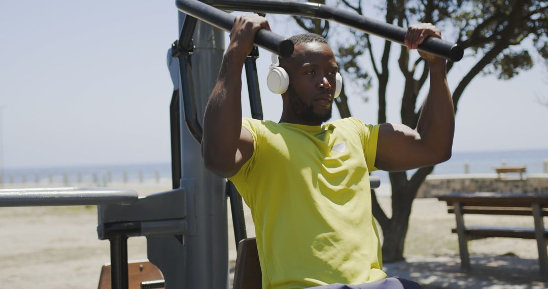 Focused Man Exercising on Outdoor Gym Equipment at Beach - Free Images, Stock Photos and Pictures on Pikwizard.com