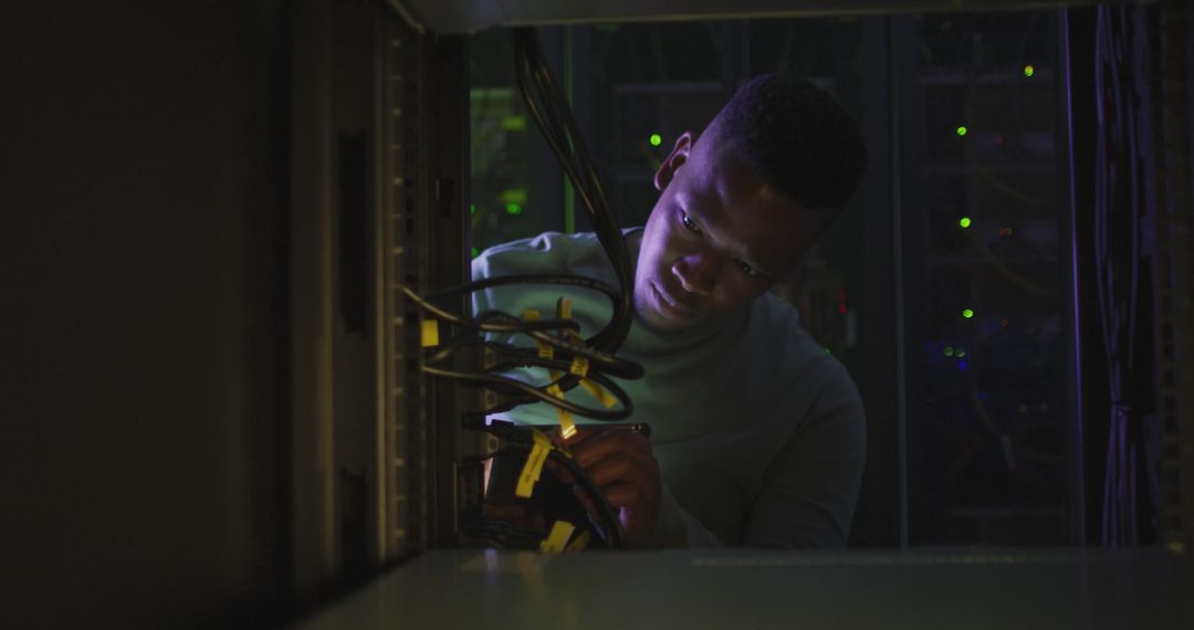 African American Technician Working with Server Racks in Low Light - Free Images, Stock Photos and Pictures on Pikwizard.com