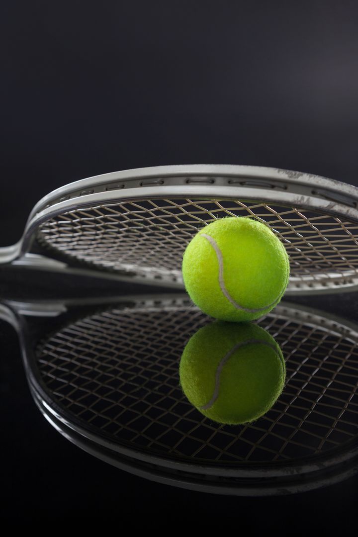 Symmetrical view of tennis racket on ball with reflection - Free Images, Stock Photos and Pictures on Pikwizard.com