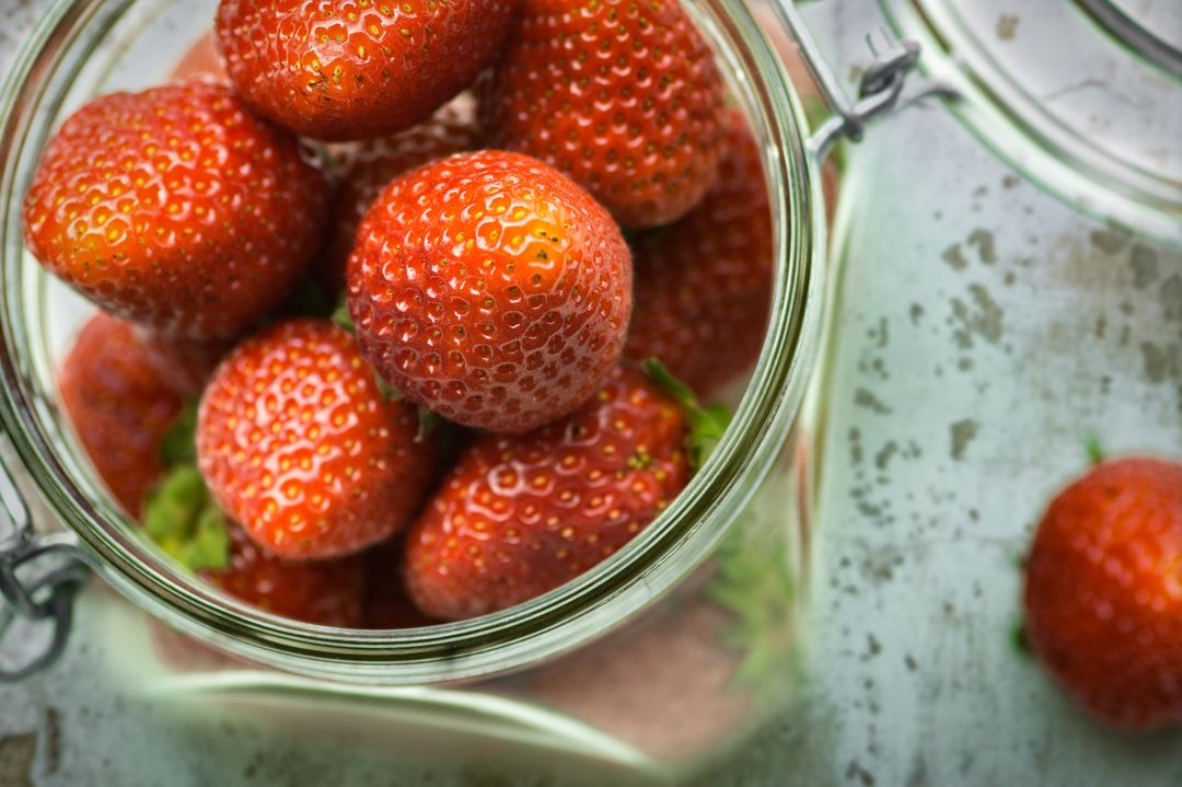 Fresh Strawberries in Glass Jar on Rustic Surface