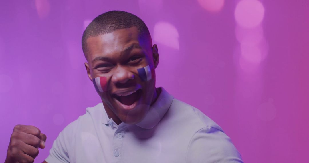 Excited Man Cheering with French Flag Face Paint under Purple Lights