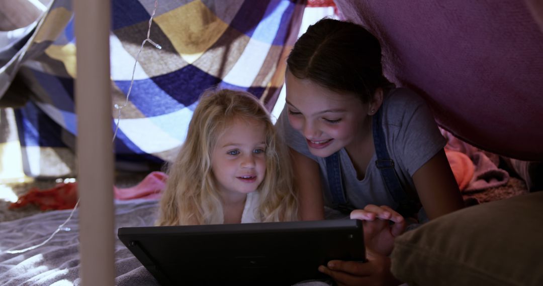 Sisters Reading Tablet in Homemade Blanket Fort - Free Images, Stock Photos and Pictures on Pikwizard.com