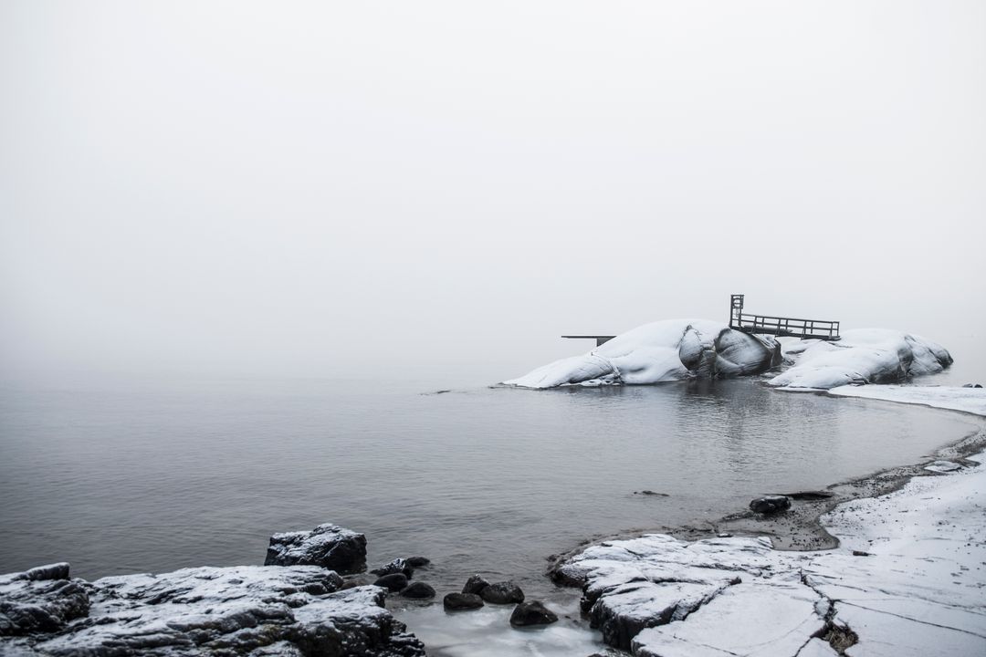 Snow-covered rocky coastline with serene foggy horizon - Free Images, Stock Photos and Pictures on Pikwizard.com