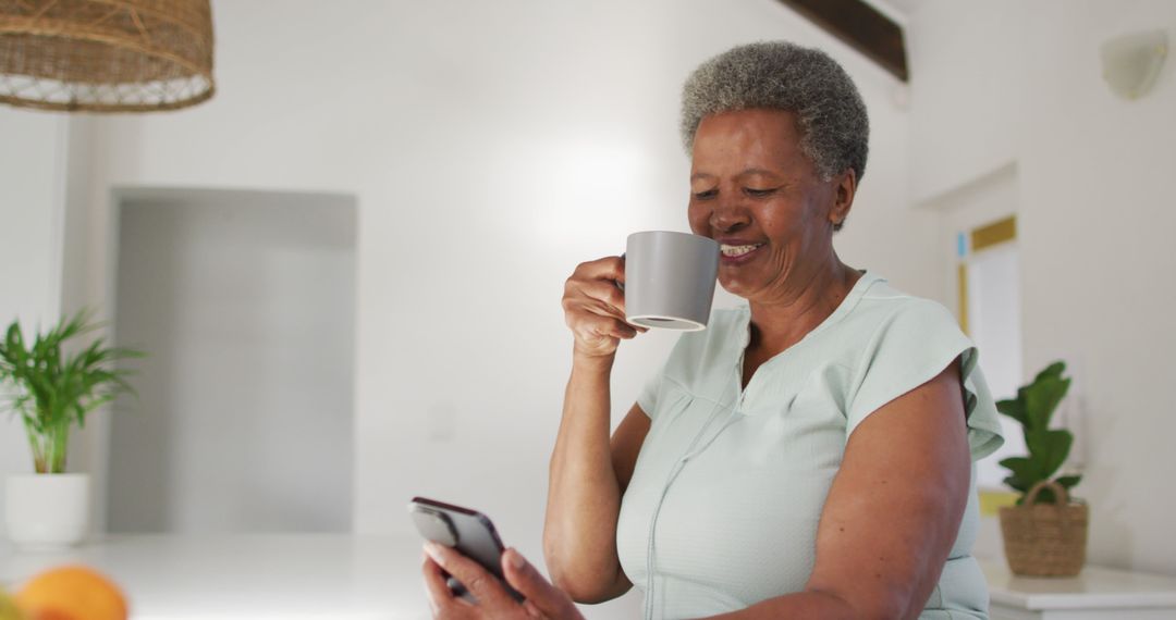 Senior Woman Enjoying Coffee While Using Smartphone in Modern Home - Free Images, Stock Photos and Pictures on Pikwizard.com