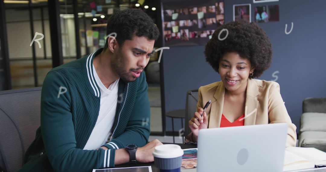 Young professionals collaborating over laptop and tablet, discussing project in coworking lounge
