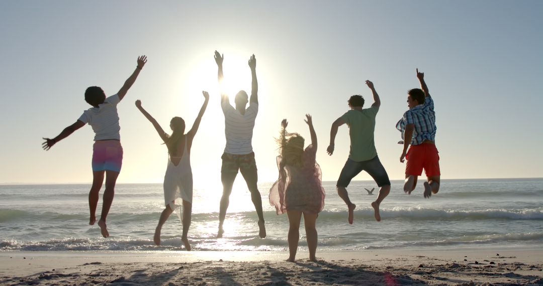 Group of Friends Jumping on Beach with Sunlit Silhouettes