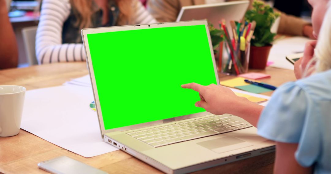 Person Pointing at Green Screen Laptop in Office Meeting - Free Images, Stock Photos and Pictures on Pikwizard.com