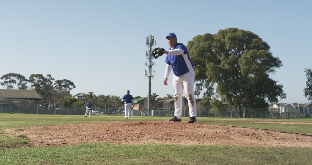 Pitcher Intensely Throwing on Baseball Field with Teammates in Background