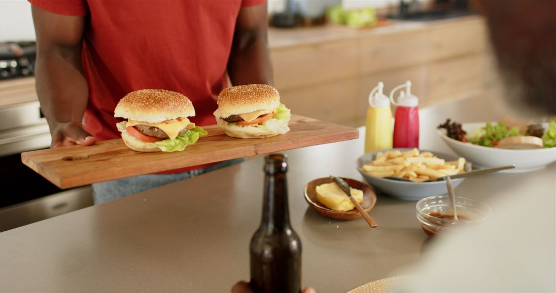 Man Presenting Burgers on Wooden Board with Fries and Condiments