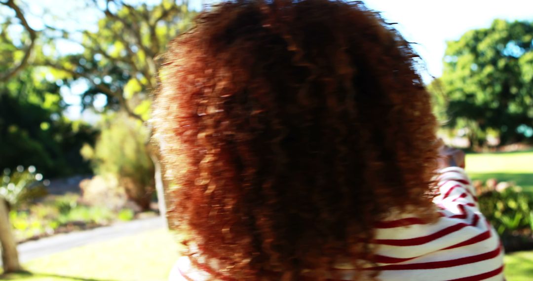 Person with Curly Hair Outdoors Pointing Toward Scenic Park - Free Images, Stock Photos and Pictures on Pikwizard.com