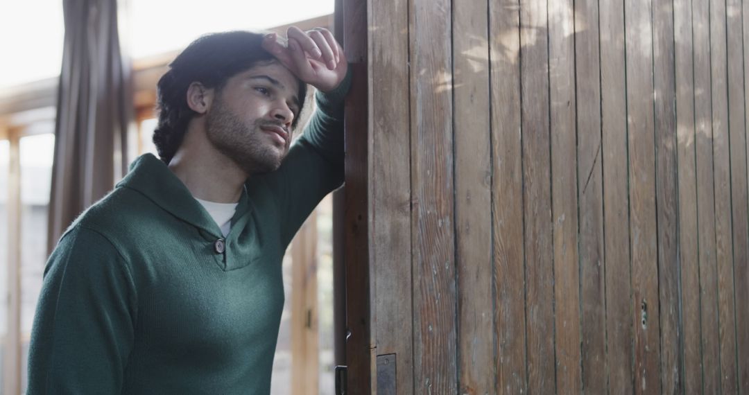 Thoughtful Man Leaning Against Wooden Doorway in Cozy Home - Free Images, Stock Photos and Pictures on Pikwizard.com