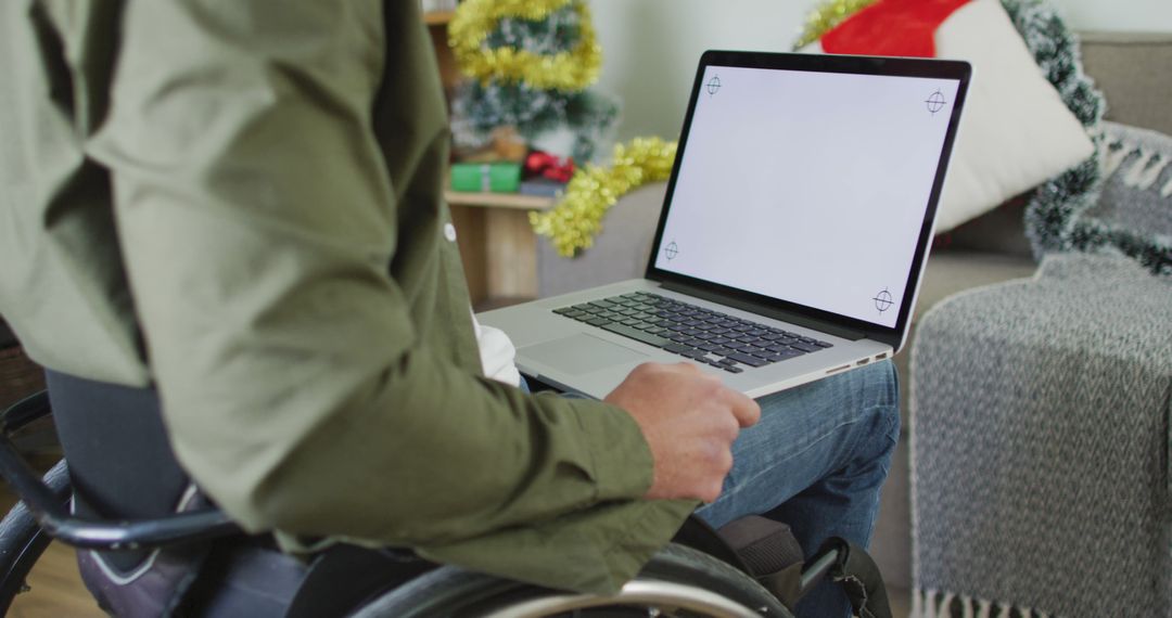 Person in wheelchair using laptop at home during holiday season - Free Images, Stock Photos and Pictures on Pikwizard.com