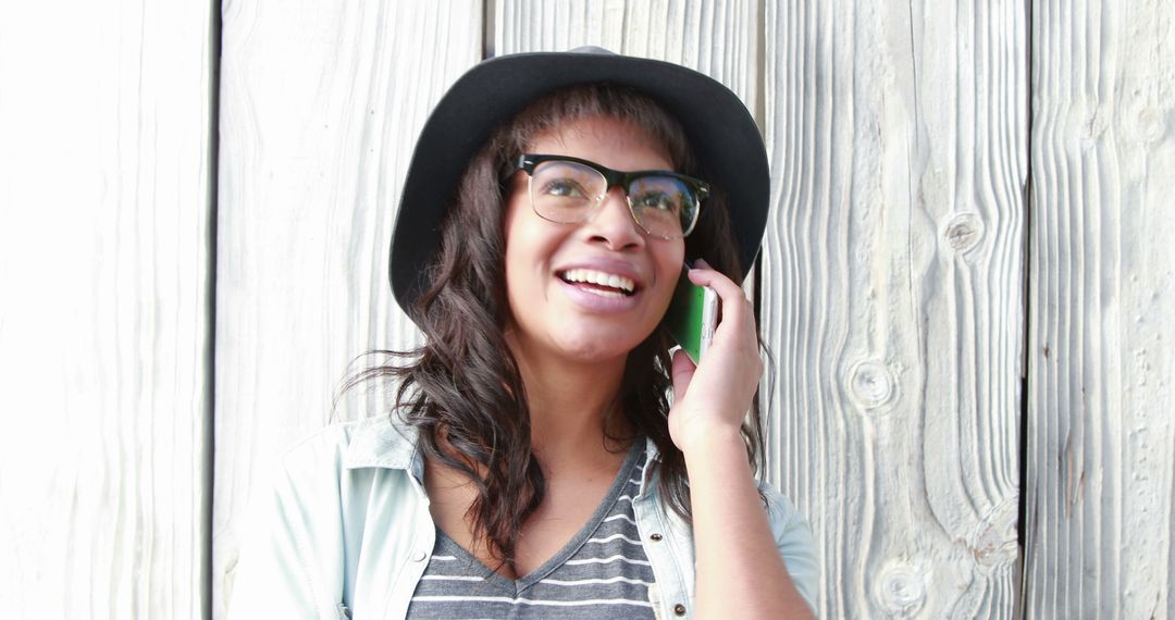 Smiling Woman Wearing Glasses and Hat Talking on Smartphone - Free Images, Stock Photos and Pictures on Pikwizard.com