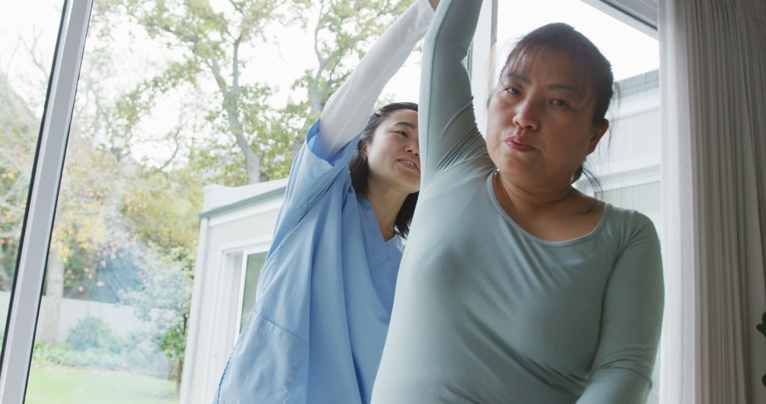 Physical Therapist Assisting Female Patient with Arm Exercise in Home Setting - Free Images, Stock Photos and Pictures on Pikwizard.com