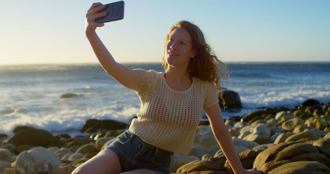 Young Woman Taking Selfie on Rocky Seashore During Sunset - Free Images, Stock Photos and Pictures on Pikwizard.com