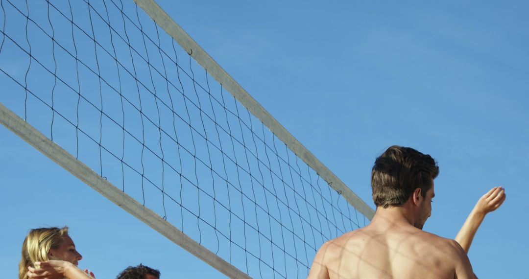 Group Playing Beach Volleyball Under Clear Blue Sky - Free Images, Stock Photos and Pictures on Pikwizard.com