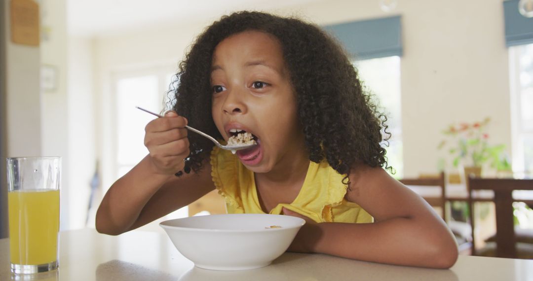 Young Girl Eating Breakfast Cereal in Kitchen - Free Images, Stock Photos and Pictures on Pikwizard.com