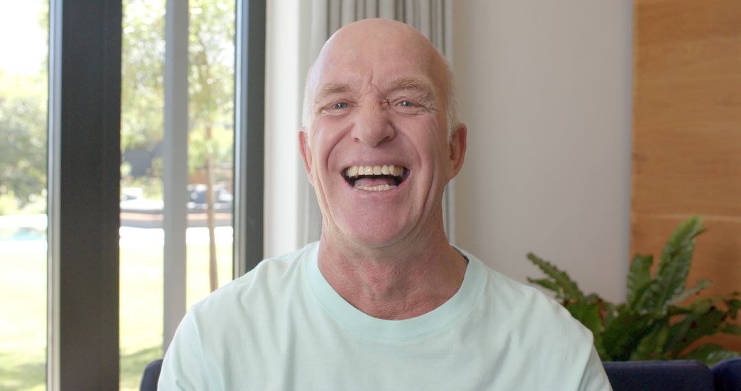 Bald Senior Man Laughing Cheerfully in Bright Living Room - Free Images, Stock Photos and Pictures on Pikwizard.com