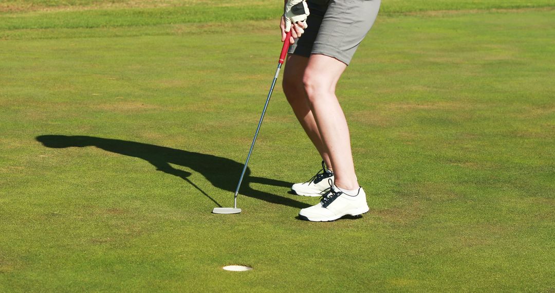 Female Golfer Putting on Green in Sunny Weather