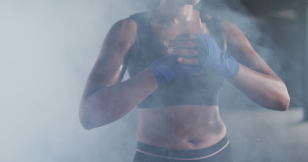 Determined Female Boxer with Blue Hand Wraps Training in Misty Session - Free Images, Stock Photos and Pictures on Pikwizard.com