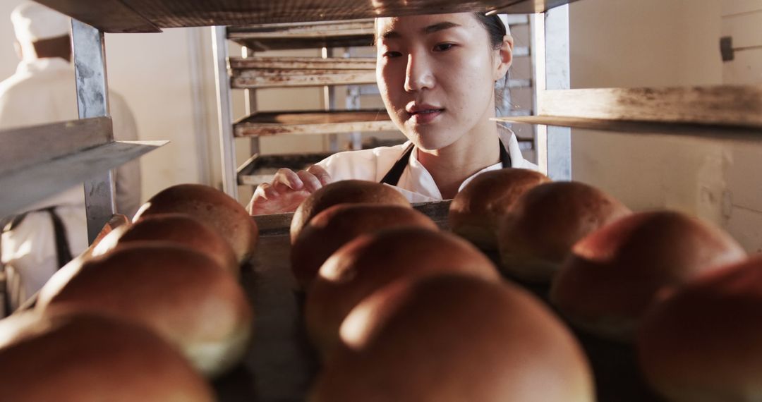 Baker Inspecting Freshly Baked Bread Rolls in Bakery - Free Images, Stock Photos and Pictures on Pikwizard.com