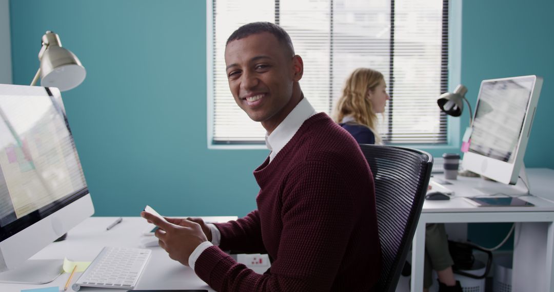 Young Professional Smiling at Desk in Modern Office Workspace - Free Images, Stock Photos and Pictures on Pikwizard.com