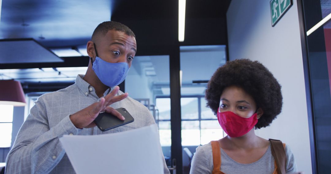 Colleagues in Office Wearing Face Masks and Discussing Documents