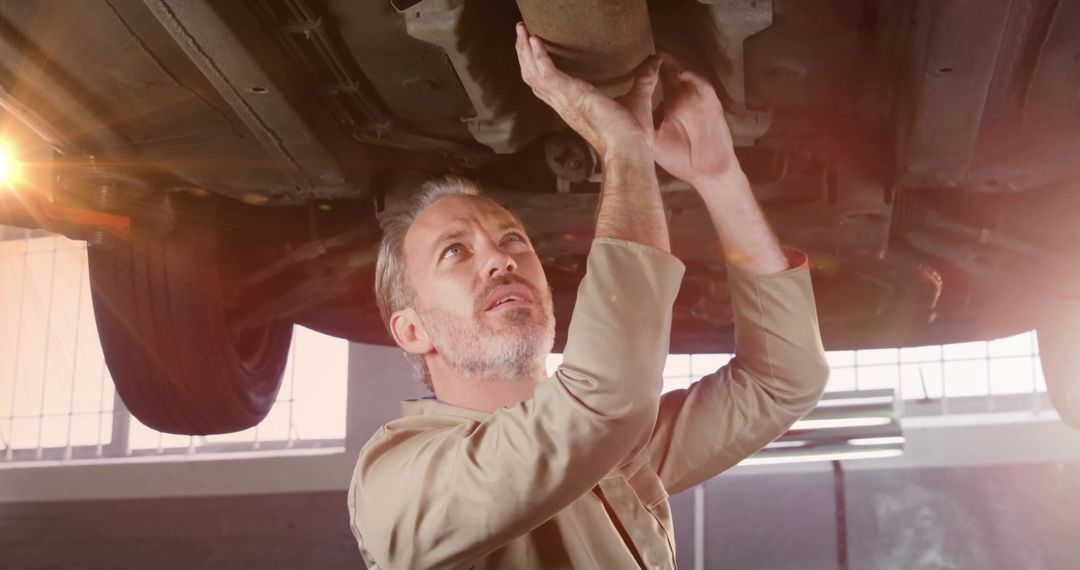 Mechanic Examining Car Exhaust System in Workshop