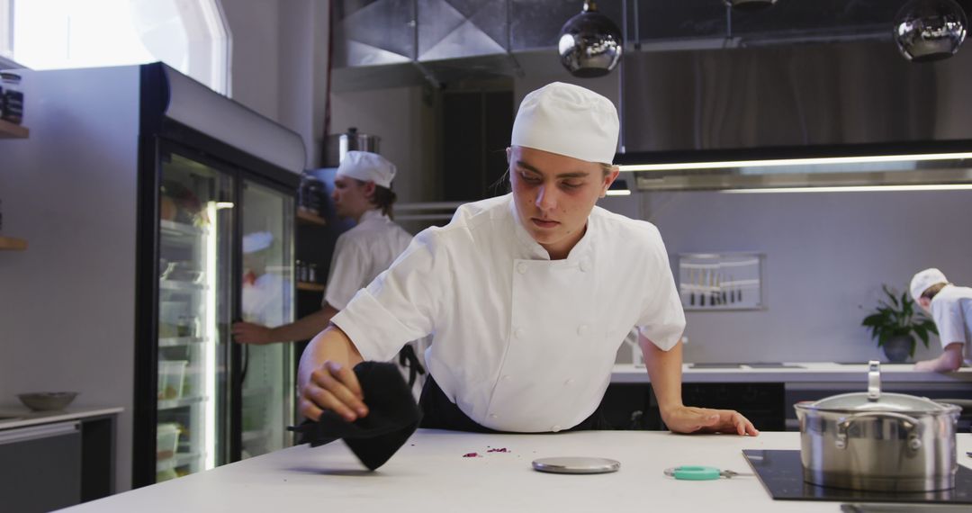 Young Chef Cleaning Kitchen Counter in Professional Restaurant - Free Images, Stock Photos and Pictures on Pikwizard.com