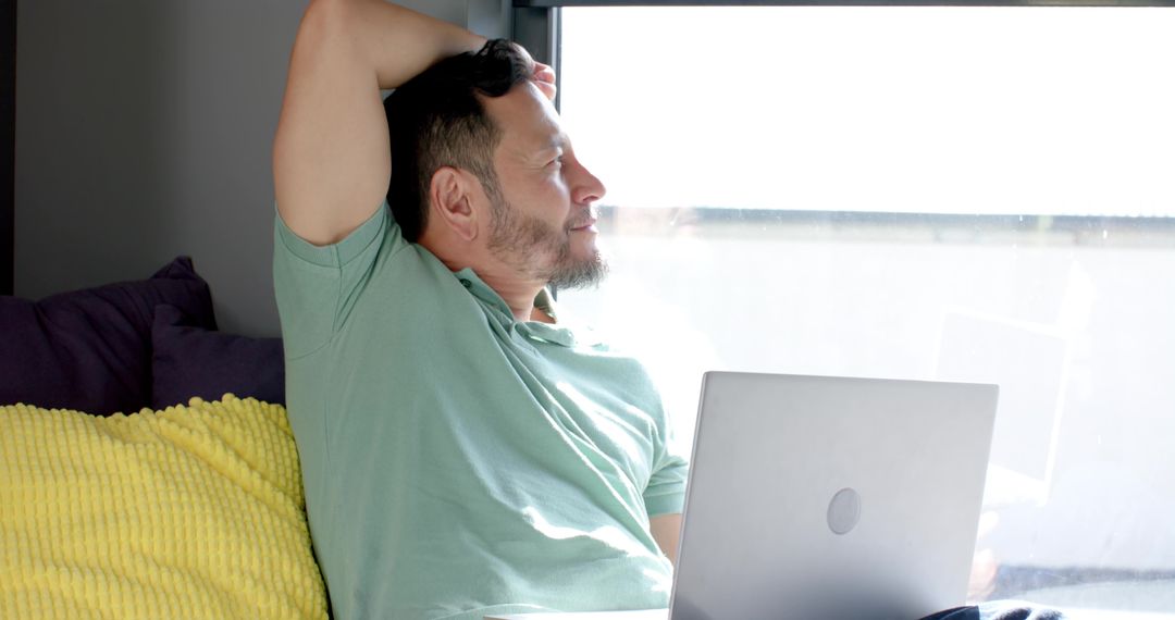 Relaxing with Laptop at Home, Man Enjoys Sunny Break on Bright Sofa
