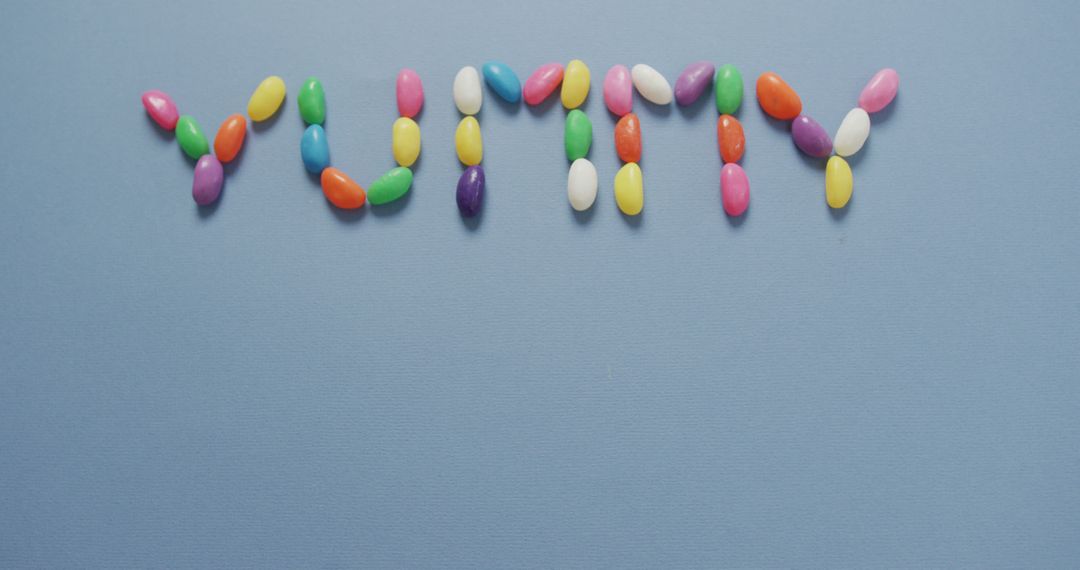 Colorful Jelly Beans Forming the Word 'Yummy' on Blue Background - Free Images, Stock Photos and Pictures on Pikwizard.com