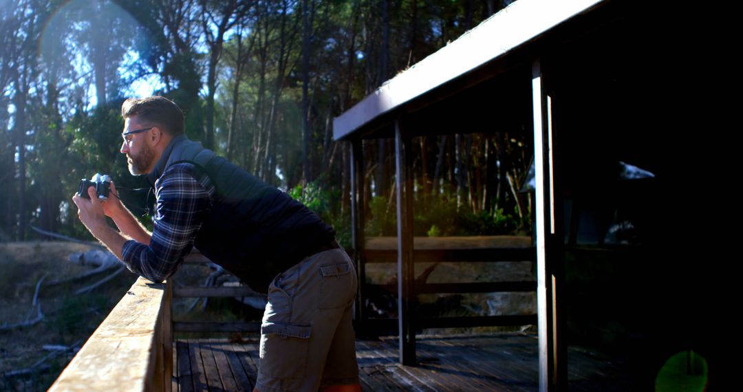 Man Enjoying Nature While Taking Photos from Wooden Cabin Deck - Free Images, Stock Photos and Pictures on Pikwizard.com