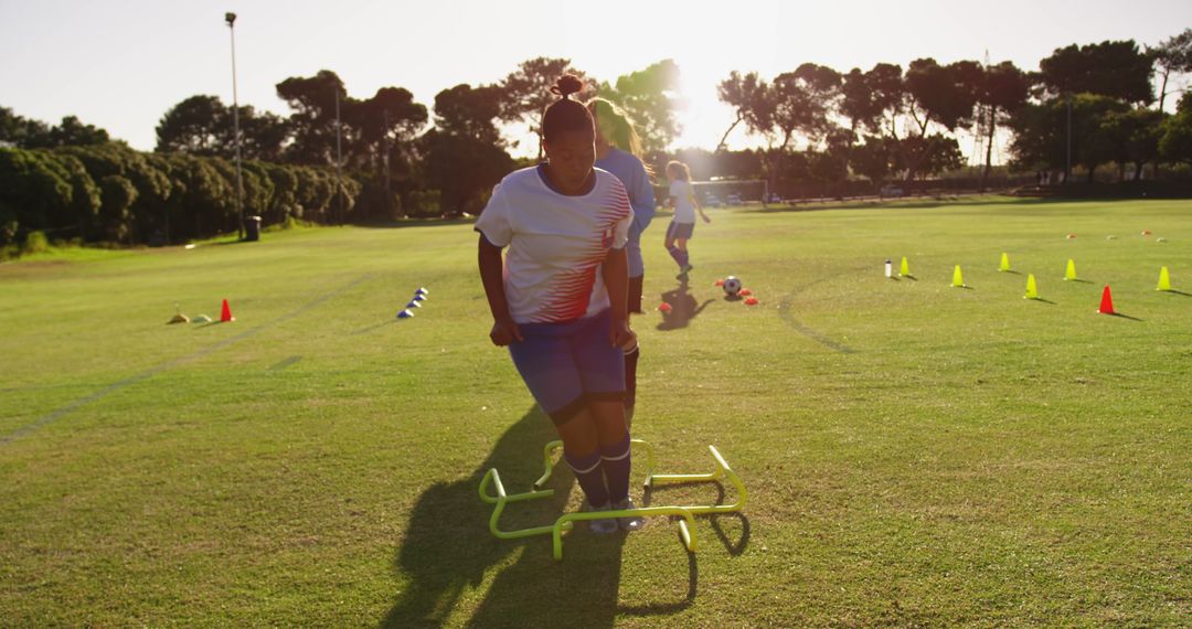 Female Soccer Player Training on Field with Hurdles at Sunset - Free Images, Stock Photos and Pictures on Pikwizard.com