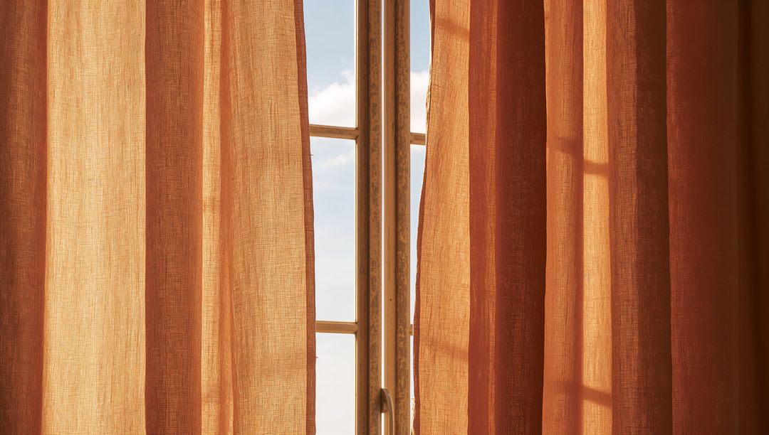 Sunlit Terracotta Curtains Revealing Paned Window Frame with Soft Shadow Patterns